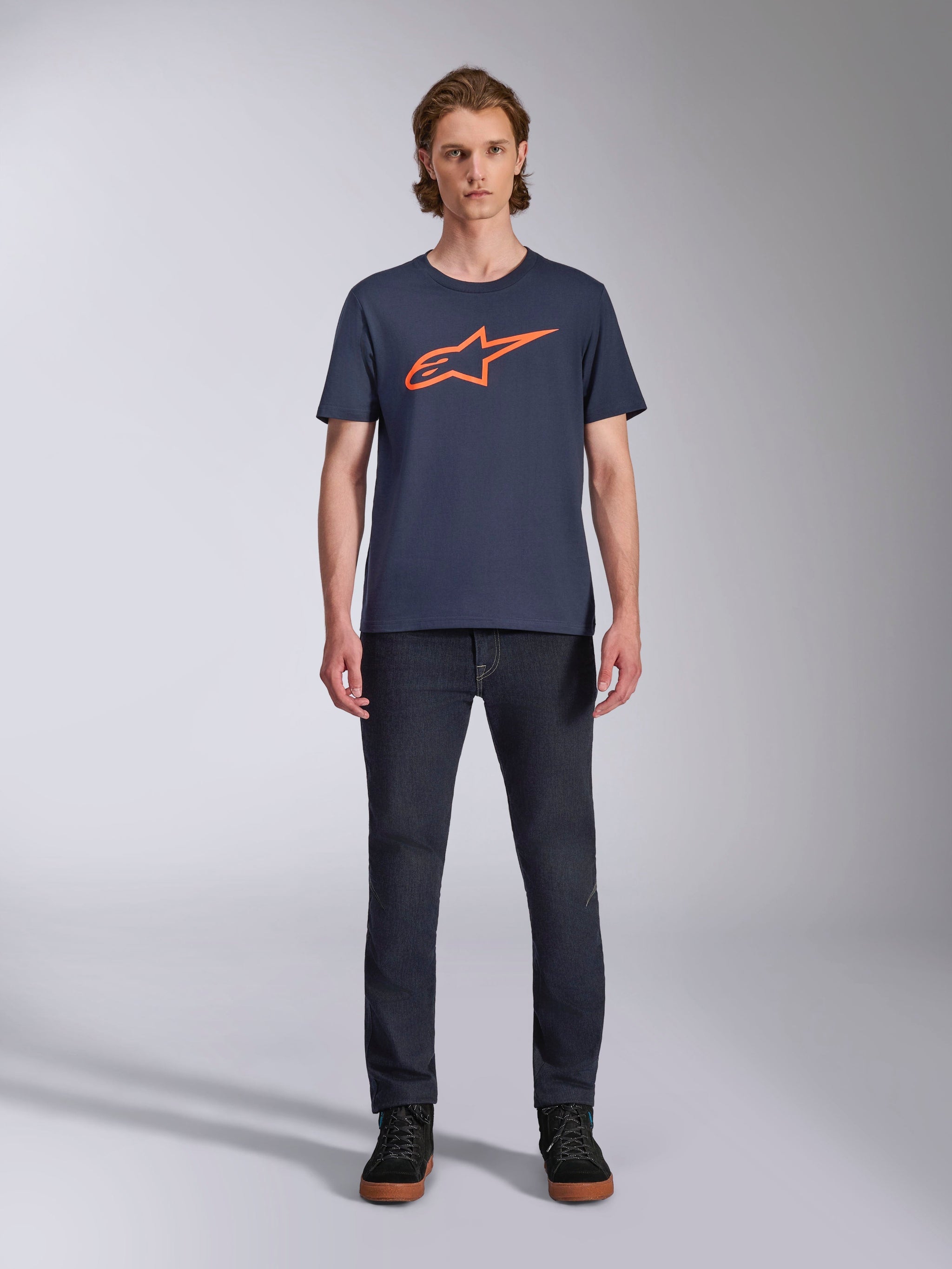 Alpinestars Ageless 2.0 CSF Tee, Short Sleeve T-Shirt, Navy Blue with Orange Alpinestars Logo, worn by model with dark jeans and sneakers, Casual Motorsport Streetwear