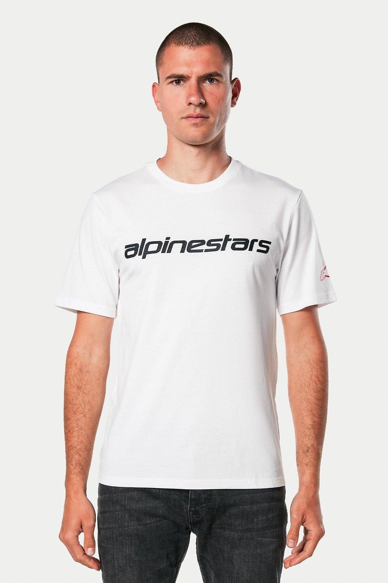 Alpinestars Linear Wordmark 2.0 CSF Tee, Short Sleeve T-Shirt, White with Black linear wordmark on chest and red logo on sleeve, worn by model with dark jeans, casual motorsport streetwear