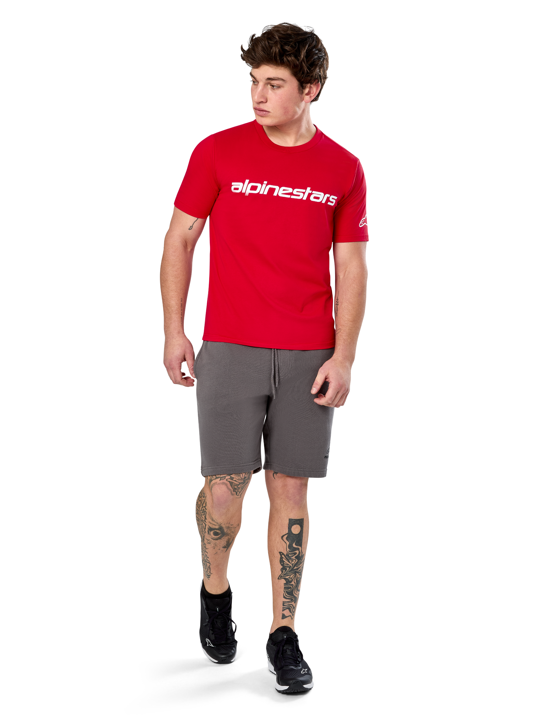 Alpinestars Linear Wordmark 2.0 CSF Tee, Short Sleeve T-Shirt, Red with white wordmark logo on chest, worn by model with grey shorts and black sneakers, casual motorsport-inspired streetwear