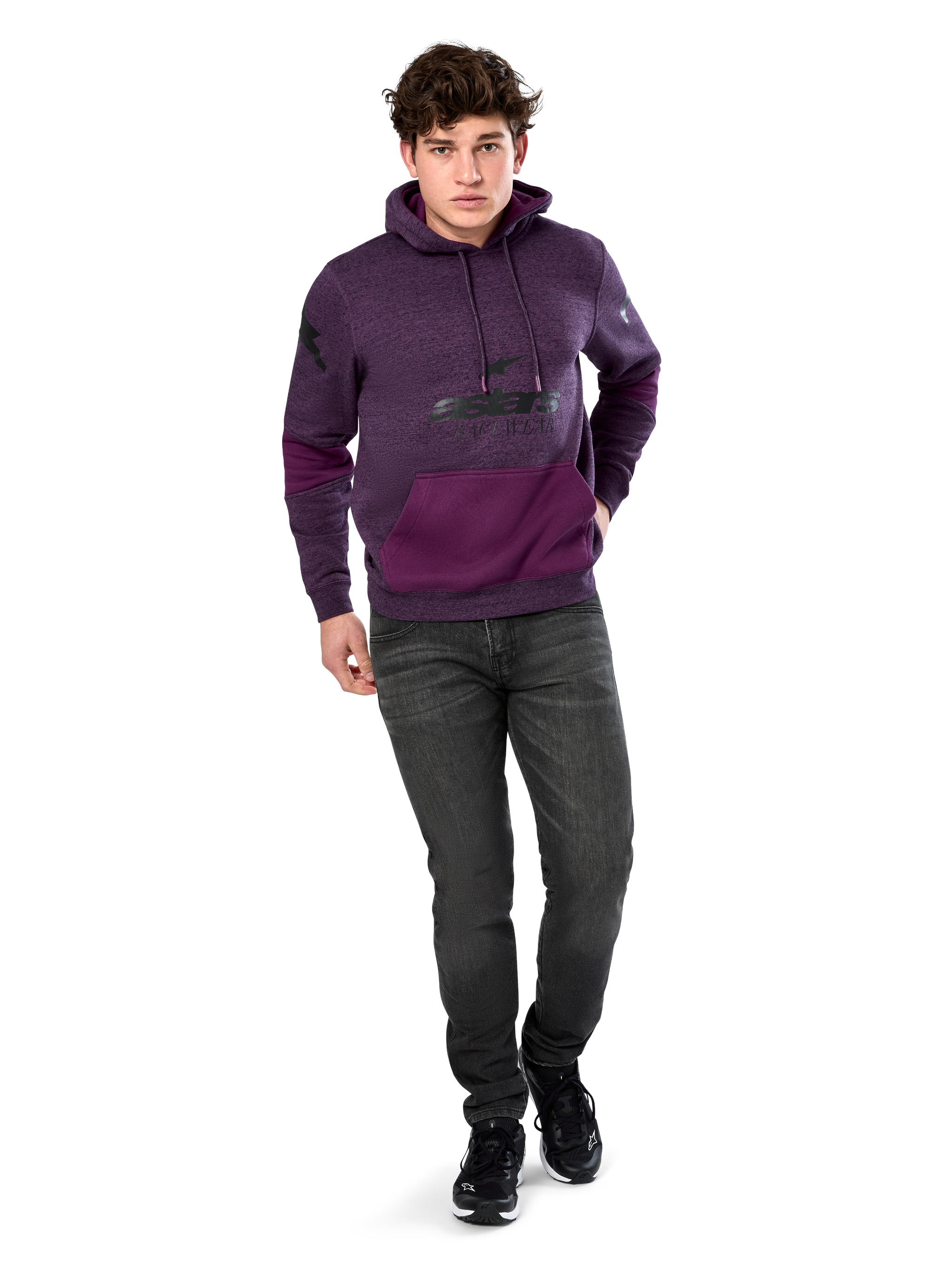 Alpinestars Perpetuate Hoodie, casual streetwear, purple heather fleece with dark purple fabric blocking on the kangaroo pocket and sleeves, black chest logo, drawstring hood, worn by model with dark grey jeans and black sneakers