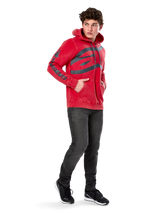 Alpinestars Unbound Hoodie, Red garment-dyed pullover fleece, extra-large dark logo on chest and wordmark on sleeves, kangaroo pocket, drawstring hood, worn by model with dark gray jeans and black sneakers, casual motorsport-inspired streetwear