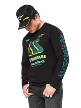 Alpinestars Ayess CSF Long Sleeve Tee, Black long sleeve shirt with neon yellow and cyan graphics, large AS chest logo and vertical Alpinestars branding on the sleeve, worn by a model with a matching black cap and dark jeans, casual motorsport lifestyle apparel