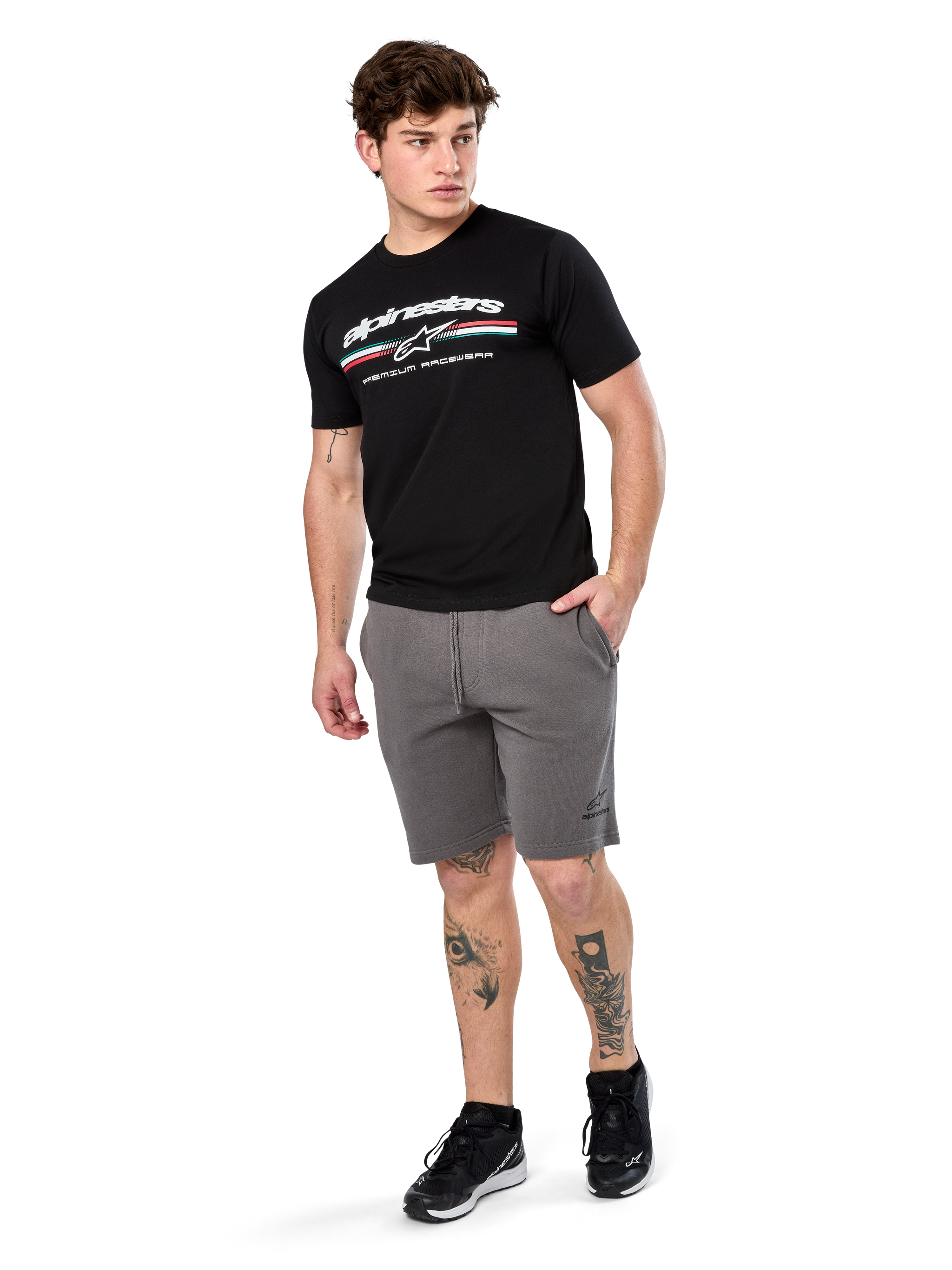 Alpinestars Prevail Csf Tee, Short Sleeve T-Shirt, Black, white Alpinestars logo with tri-color paddock stripe, worn with grey shorts and black sneakers, casual motorsport streetwear