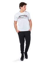 Alpinestars Prevail CSF Tee, Short Sleeve T-Shirt, White, featuring a front paddock-style tri-color stripe logo with Alpinestars branding, worn by a model with black joggers and black sneakers, casual motorsport streetwear