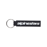 Alpinestars Linear Key Fob, Black rectangular keychain with white Alpinestars logo, silver metal ring, premium 3D molded PVC construction, motorsport-inspired accessory