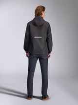 Alpinestars Speeder Chromium Windbreak Jacket, Black, back view with white Alpinestars branding across the middle, hooded style, worn by model with dark denim pants, casual motorsport-inspired jacket