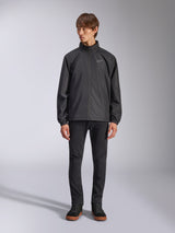 Alpinestars Overhaul Racer Jacket, Black Men's Rain Shell, full-length view on a model paired with black pants and casual sneakers, featuring a small white logo on the chest, water-resistant fabric, and casual motorsport-inspired design
