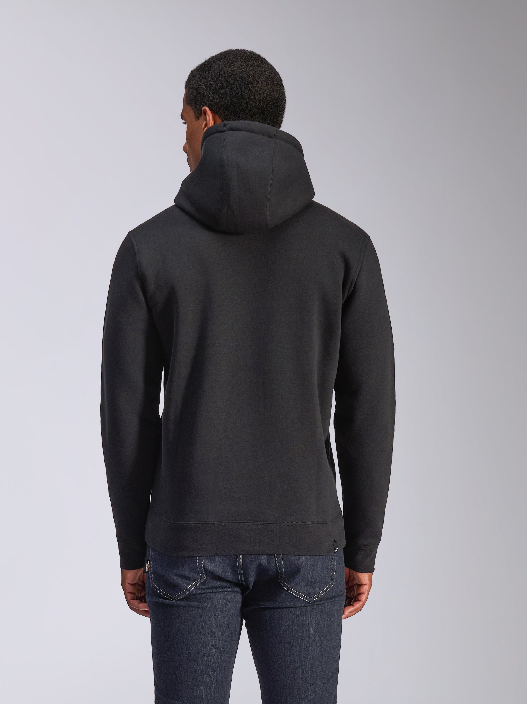 Alpinestars Blaze V3 Hoodie, rear view of black pullover fleece hoodie, casual streetwear, featuring ribbed cuffs and hem, jersey-lined hood, worn with dark blue jeans
