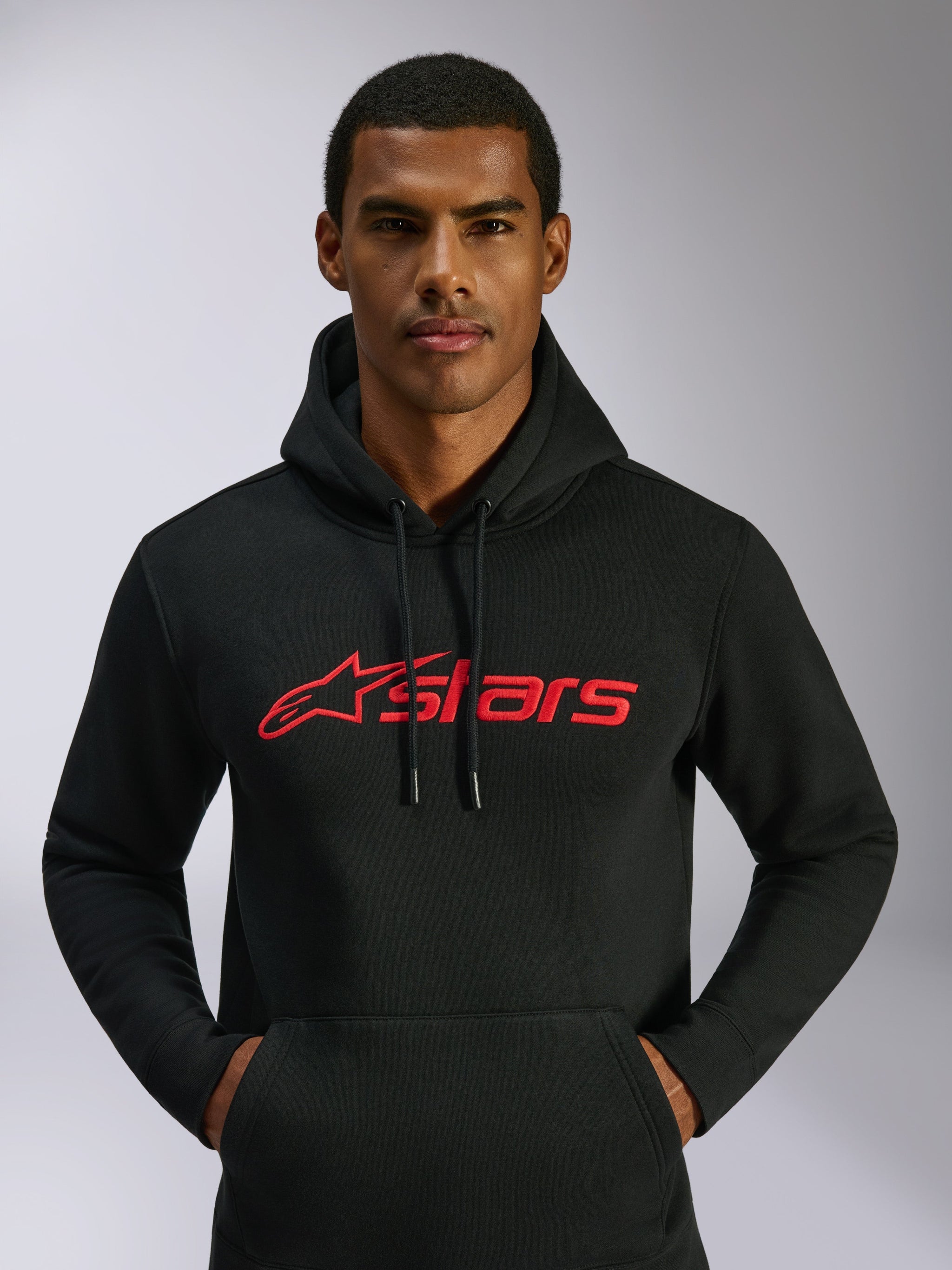Alpinestars Blaze V3 Hoodie, casual streetwear, black with red Alpinestars logo on the chest, worn by a man, drawstring hood, long sleeves, modern motorsport-inspired design