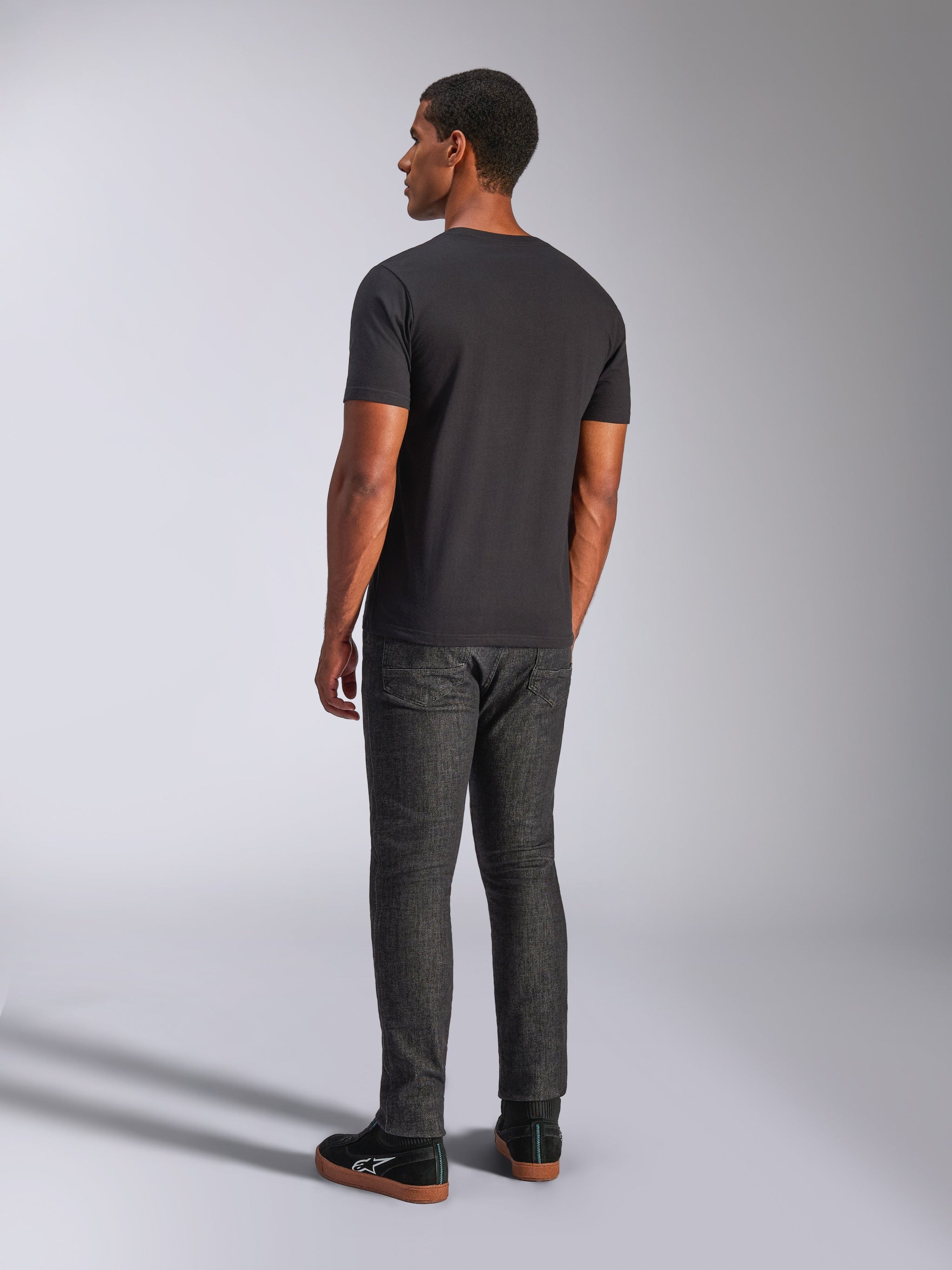 Alpinestars Heritage Patch CSF Tee, Short Sleeve T-Shirt, Black, back view on model, casual motorsport streetwear, paired with dark denim jeans and black sneakers