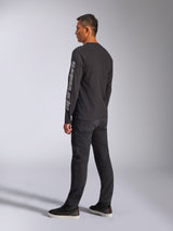 Alpinestars Trackside CSF Long Sleeve Tee, Black, featuring large grey Alpinestars logo on the left sleeve, worn by model with black pants and casual sneakers, motorsport-inspired casual streetwear.