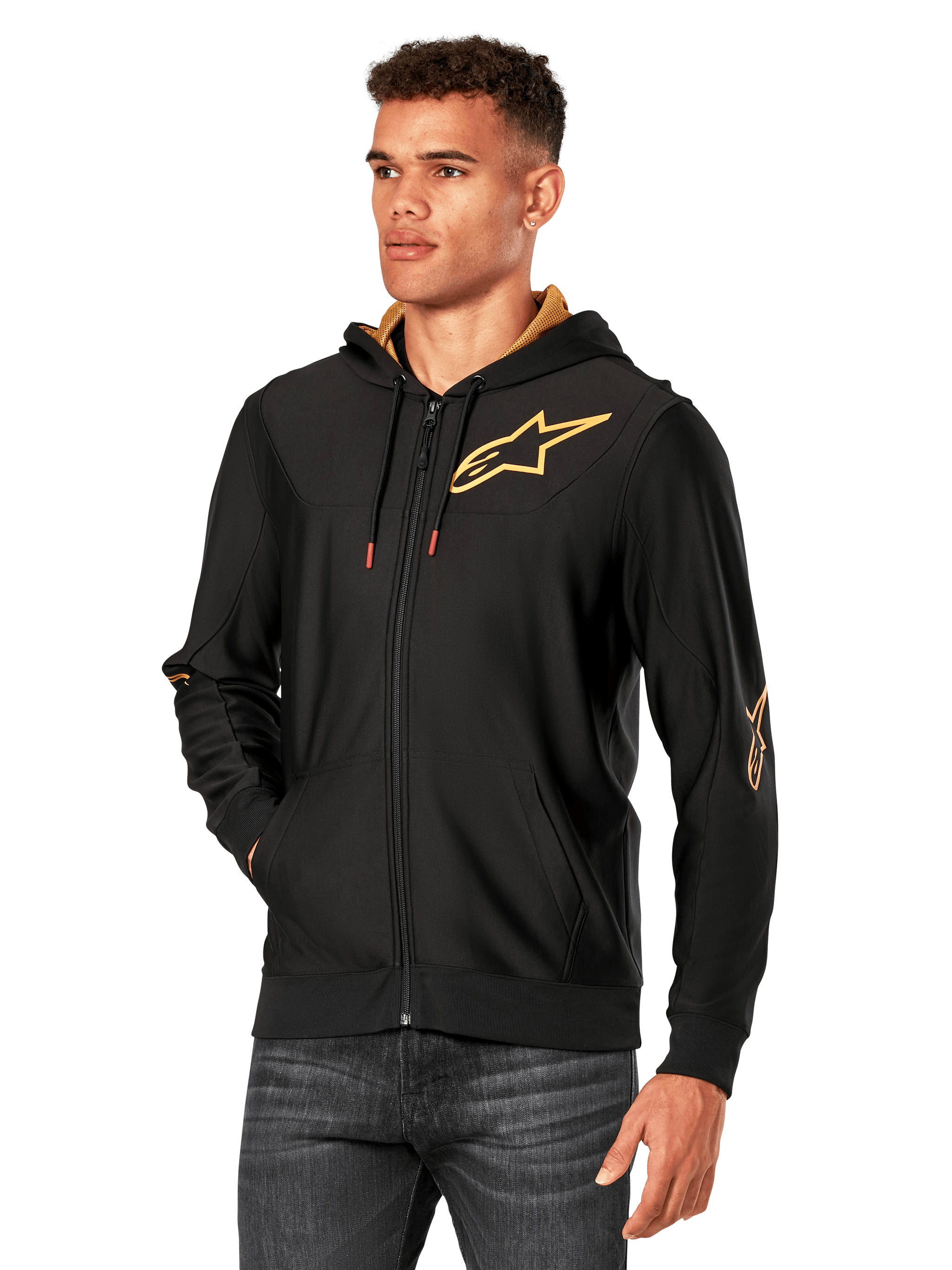 Alpinestars Sessions V3 Hoodie, Black with Gold logos, zip-up fleece hoodie worn by a model with dark jeans, featuring a gold mesh-lined hood and red-tipped drawcords, casual motorsport-inspired streetwear