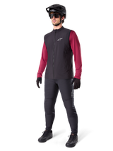 Alpinestars A-Dura Thermal Vest, Black cycling vest, worn by a rider over a maroon long-sleeve jersey and black pants, featuring a black MTB helmet and gloves, designed for cold-weather mountain biking