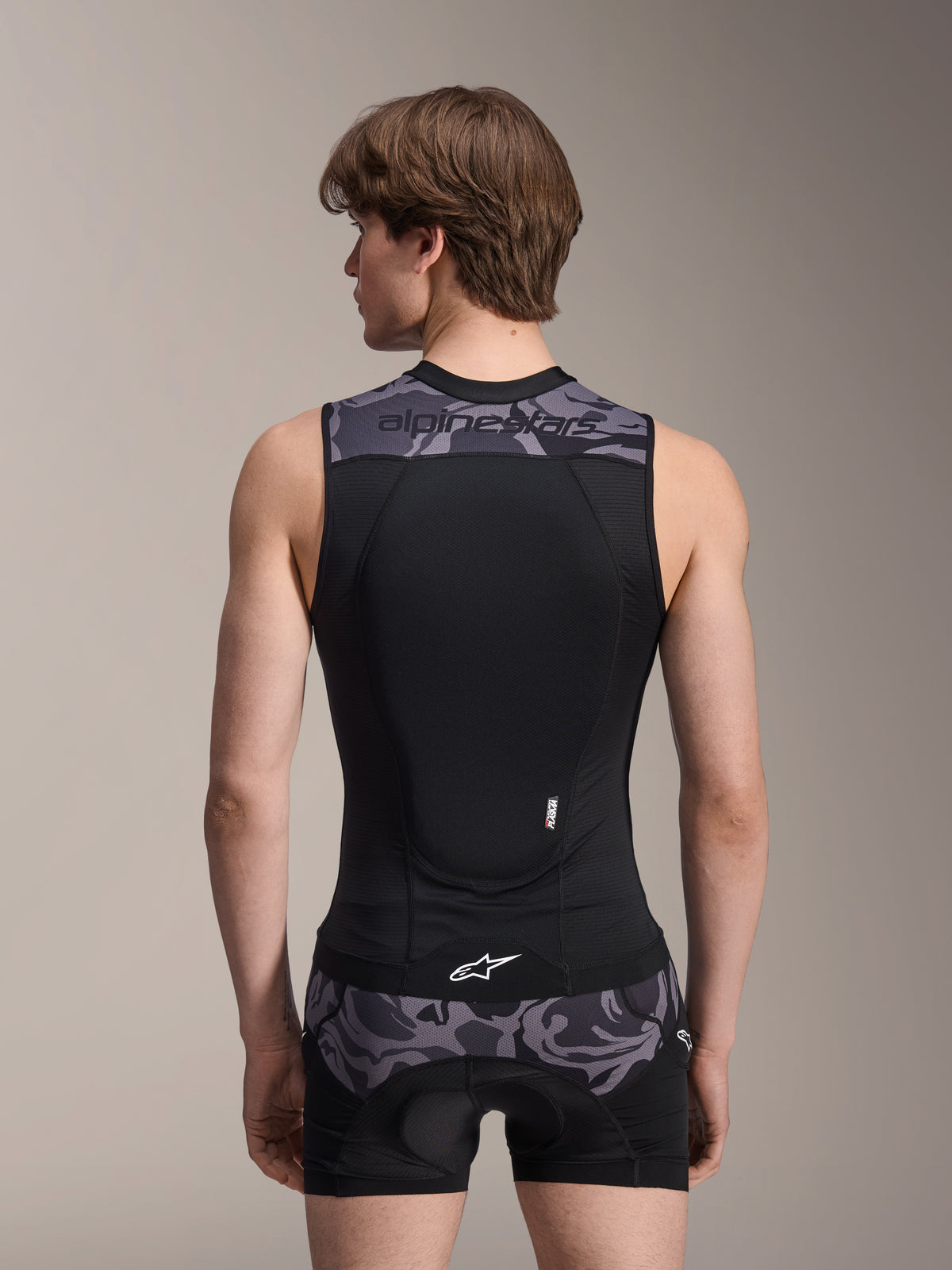 Alpinestars A-Motion Plasma Protection Vest, Black Camo, back view on male model, featuring breathable mesh construction with an integrated Nucleon Plasma back protector, grey camouflage accents on the shoulders and waist, and Alpinestars branding.