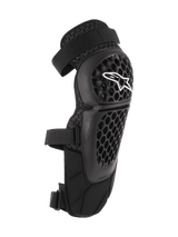 Alpinestars Bionic Plus Knee/Shin Protectors, Black, Off-road and MTB Protection, featuring a perforated honeycomb shell with a white Alpinestars logo, dual adjustable straps, and 3D mesh ventilation, ergonomic curved design
