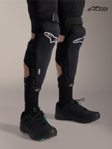 Alpinestars A-Impact Plasma Pro Knee Shin Protectors, mountain bike knee guards in black with white logo, worn by a model showcasing triple strap closure and Nucleon Plasma protection