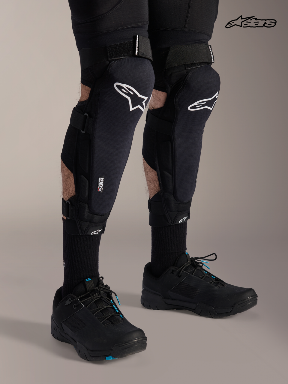 Alpinestars A-Impact Plasma Pro Knee Shin Protectors, mountain bike knee guards in black with white logo, worn by a model showcasing triple strap closure and Nucleon Plasma protection