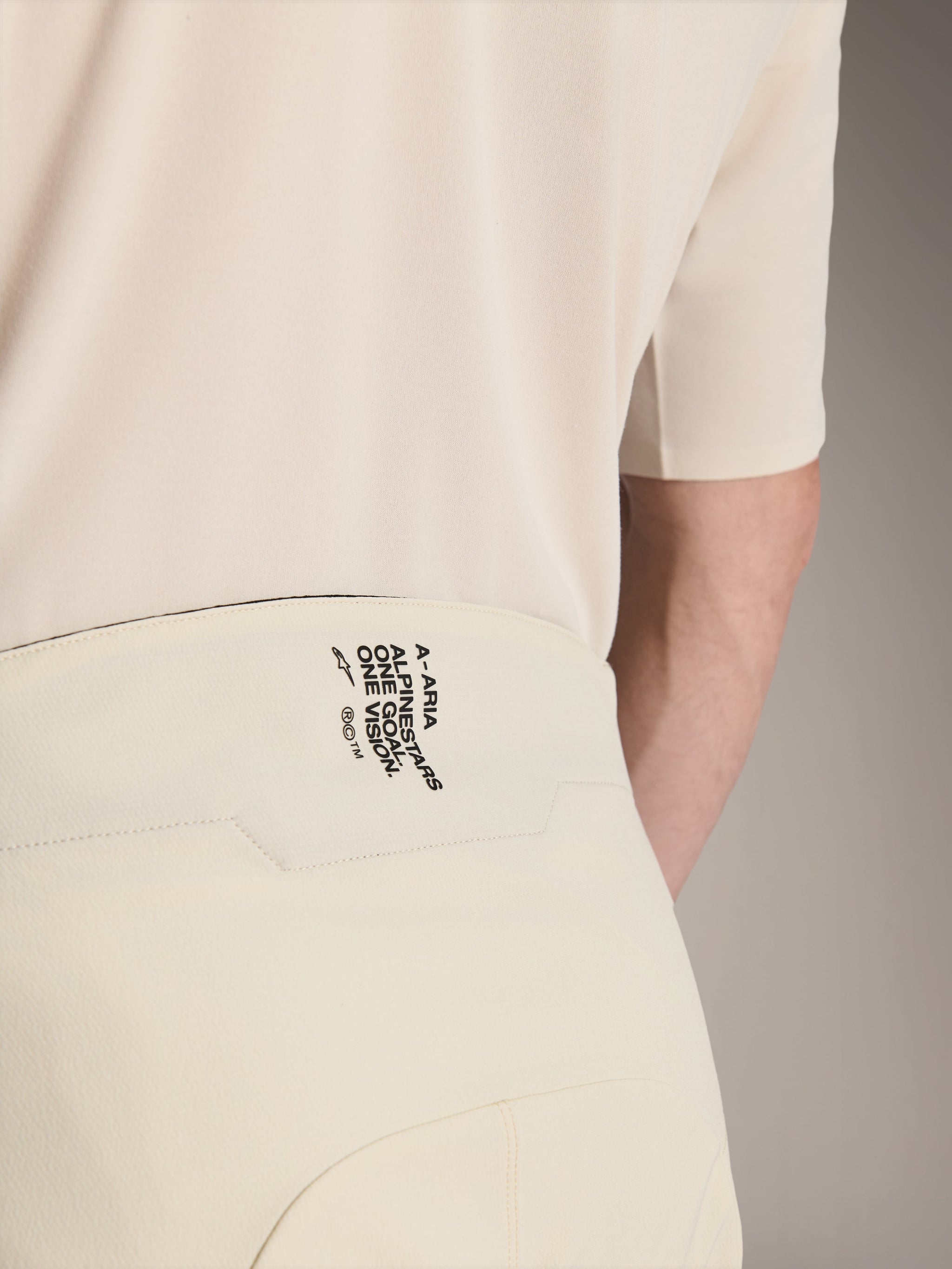 Alpinestars A-Aria Elite Shorts, Mountain Bike Shorts, Ecru color, close-up of the back waistband featuring black branding 'A-ARIA ALPINESTARS ONE GOAL. ONE VISION.', performance cycling apparel
