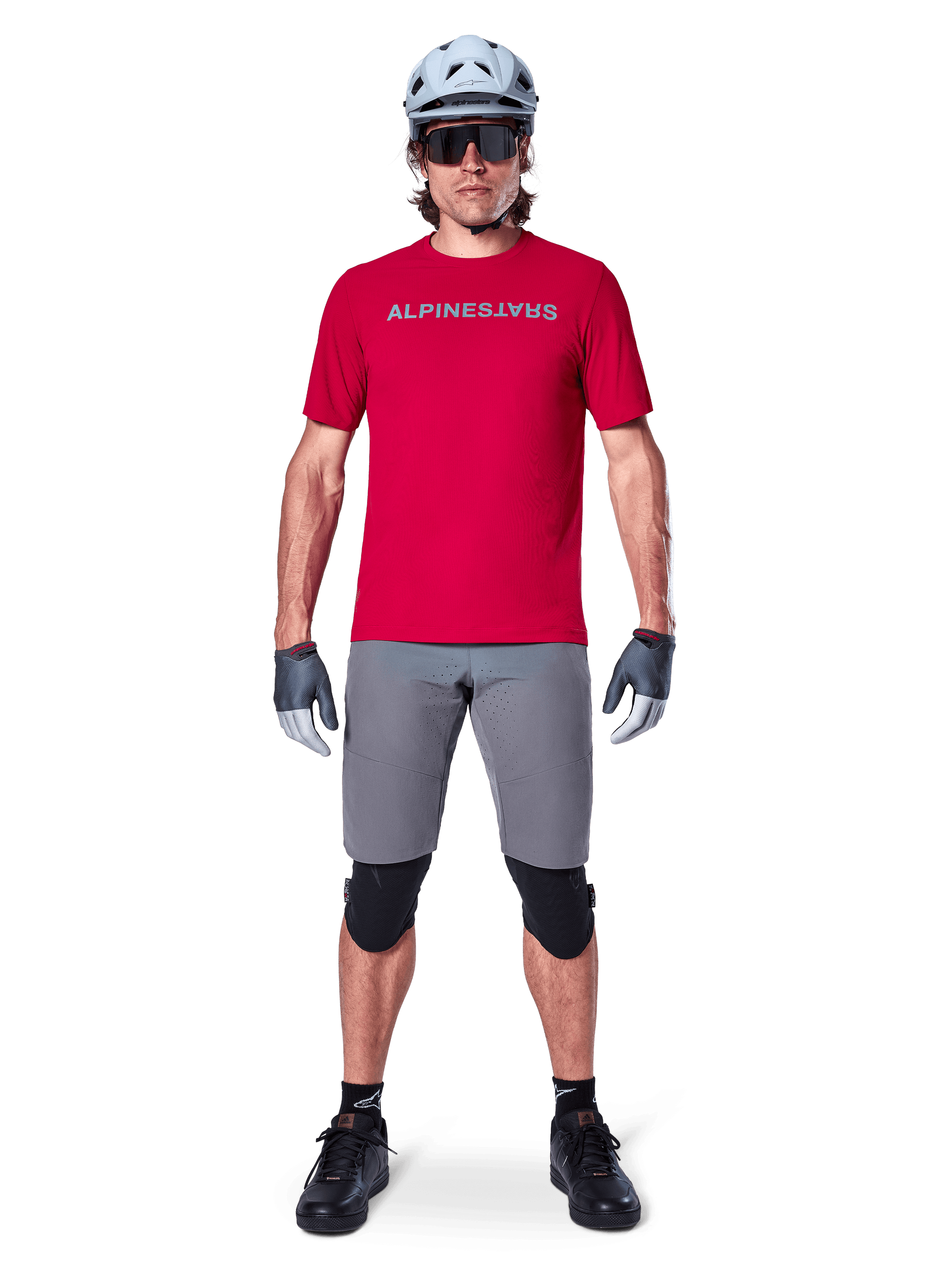 Alpinestars A-Aria Elite Shorts, Men's MTB Cycling Shorts in Dark Gray, with flexible stretch fabric and a red racing jersey.