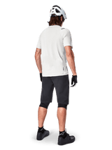 Mountain biker from behind wearing Alpinestars A-Aria Shorts in Black, white performance short-sleeve jersey, white helmet, black gloves, and black mountain bike shoes, cycling gear for trail riding