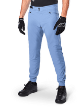 Alpinestars A-Dura Pants, Infinity Blue MTB Cycling Pants, featuring double snap front closure and zippered pockets, worn with black gloves and black shoes, durable 2-way stretch textile for off-road riding