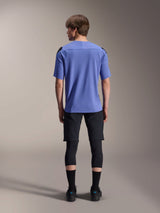 Male model from the back wearing Alpinestars mountain bike gear, light blue A-Aria Polartec Elite short sleeve jersey, black A-Aria Elite Shorts, black knee protectors, black socks, and black shoes, coordinated performance outfit for MTB.