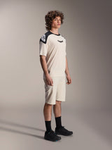 Male model wearing Alpinestars A-Aria Elite Shorts in Ecru, technical mountain bike shorts with laser-cut ventilation, paired with a matching cream and black short-sleeve jersey and black shoes, professional cycling apparel.