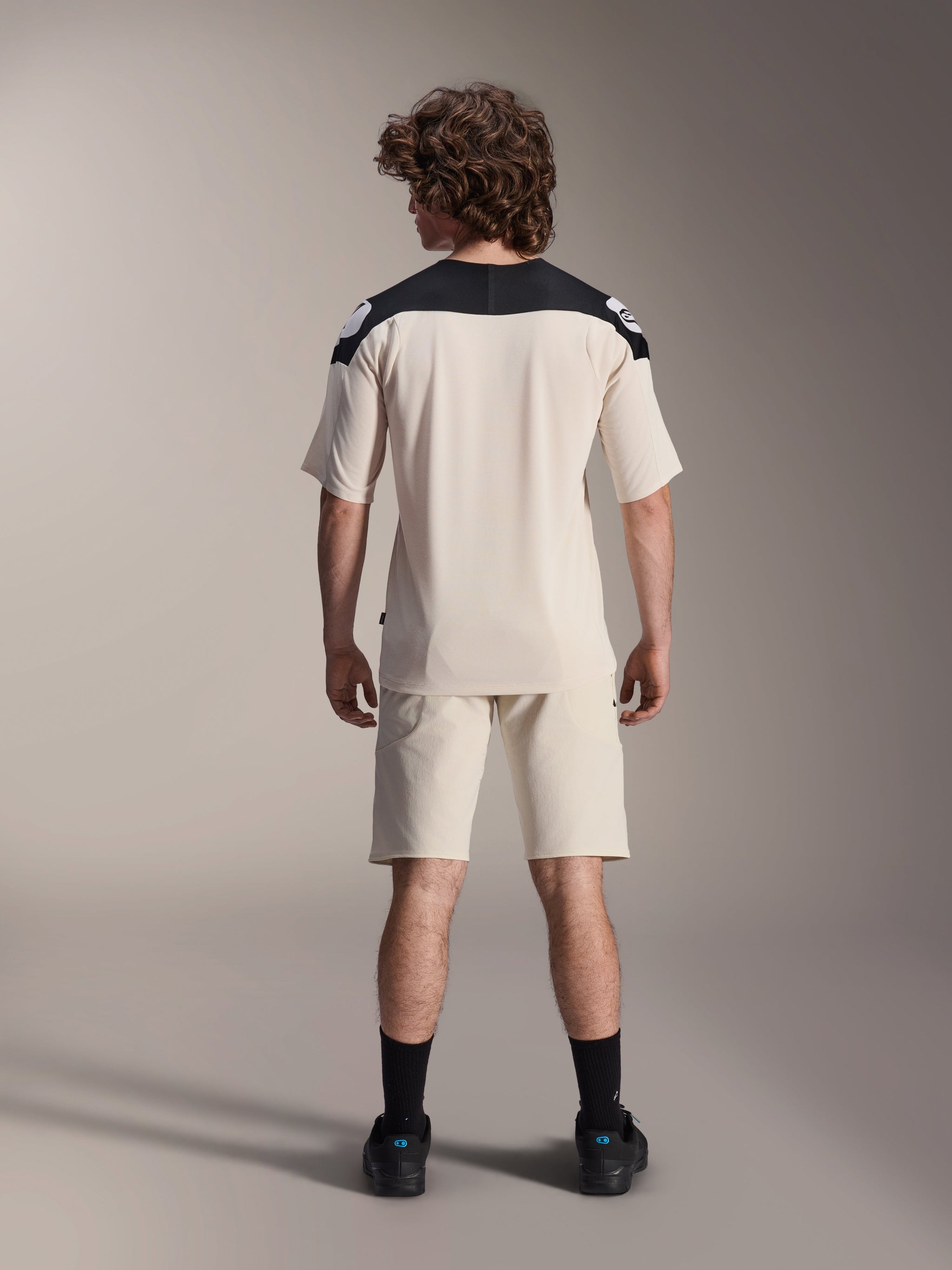 Alpinestars A-Aria Elite Shorts and A-Aria Polartec Elite SS Jersey, Ecru with black shoulder panels, rear view of a model in mountain bike performance gear, styled with black socks and shoes