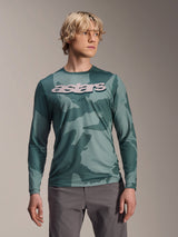 Alpinestars A-Dura Hollow Camo Long Sleeve Jersey, MTB Jersey, Silver Pine Camo green camouflage pattern, large light grey astars logo on chest, worn with grey pants, high-performance mountain biking apparel