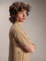 Alpinestars A-Dura Astar Jersey, Short Sleeve MTB Jersey, Light Brown, side view of a model with wavy hair wearing the textured jacquard jersey, featuring the A-Dura logo on the lower side, casual mountain bike performance style