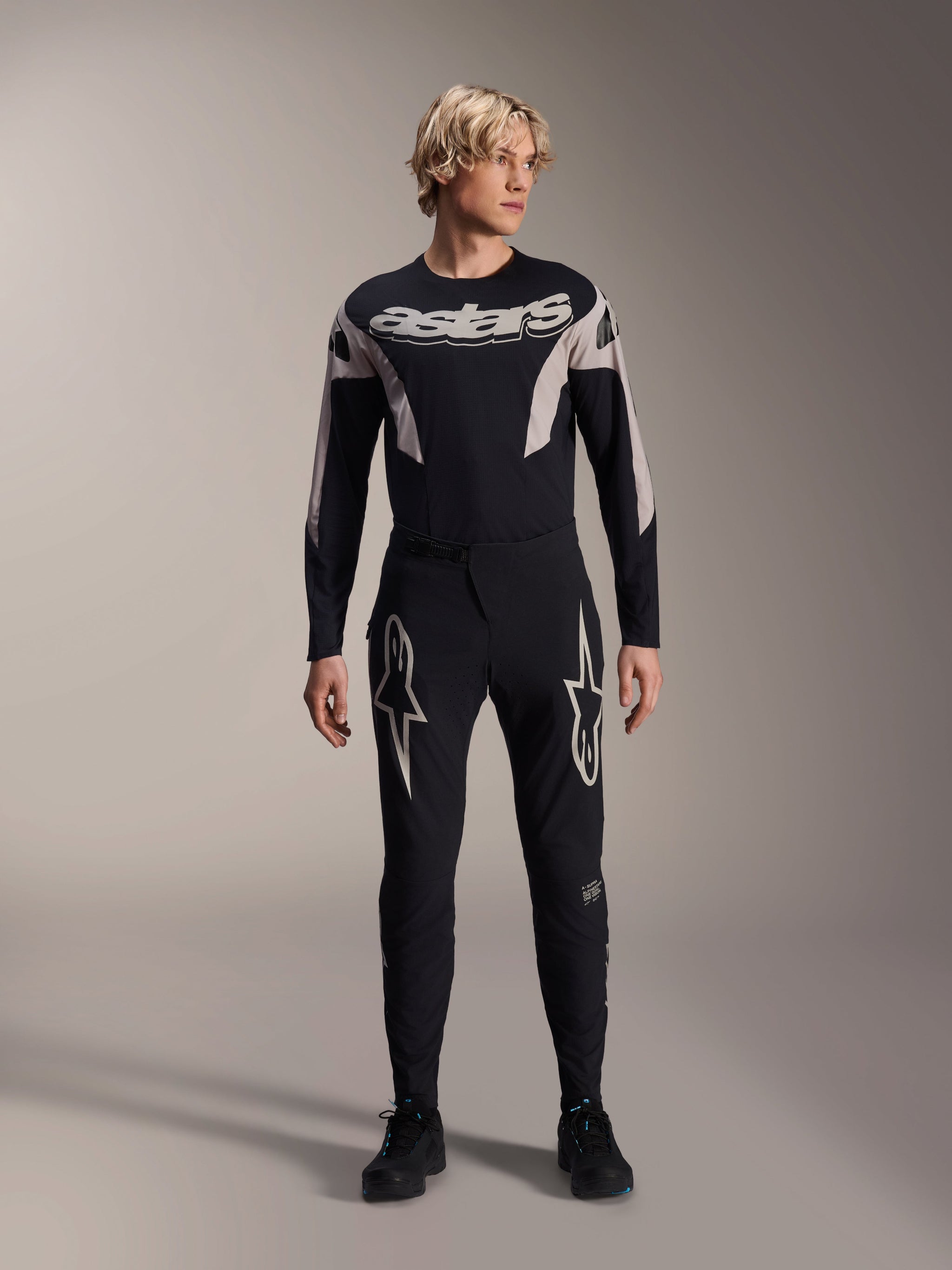 Alpinestars A-Supra Melt Jersey, Long Sleeve MTB Jersey, Black with white Astars branding across the chest, worn with matching black mountain bike pants featuring star logos, sleek performance cycling gear