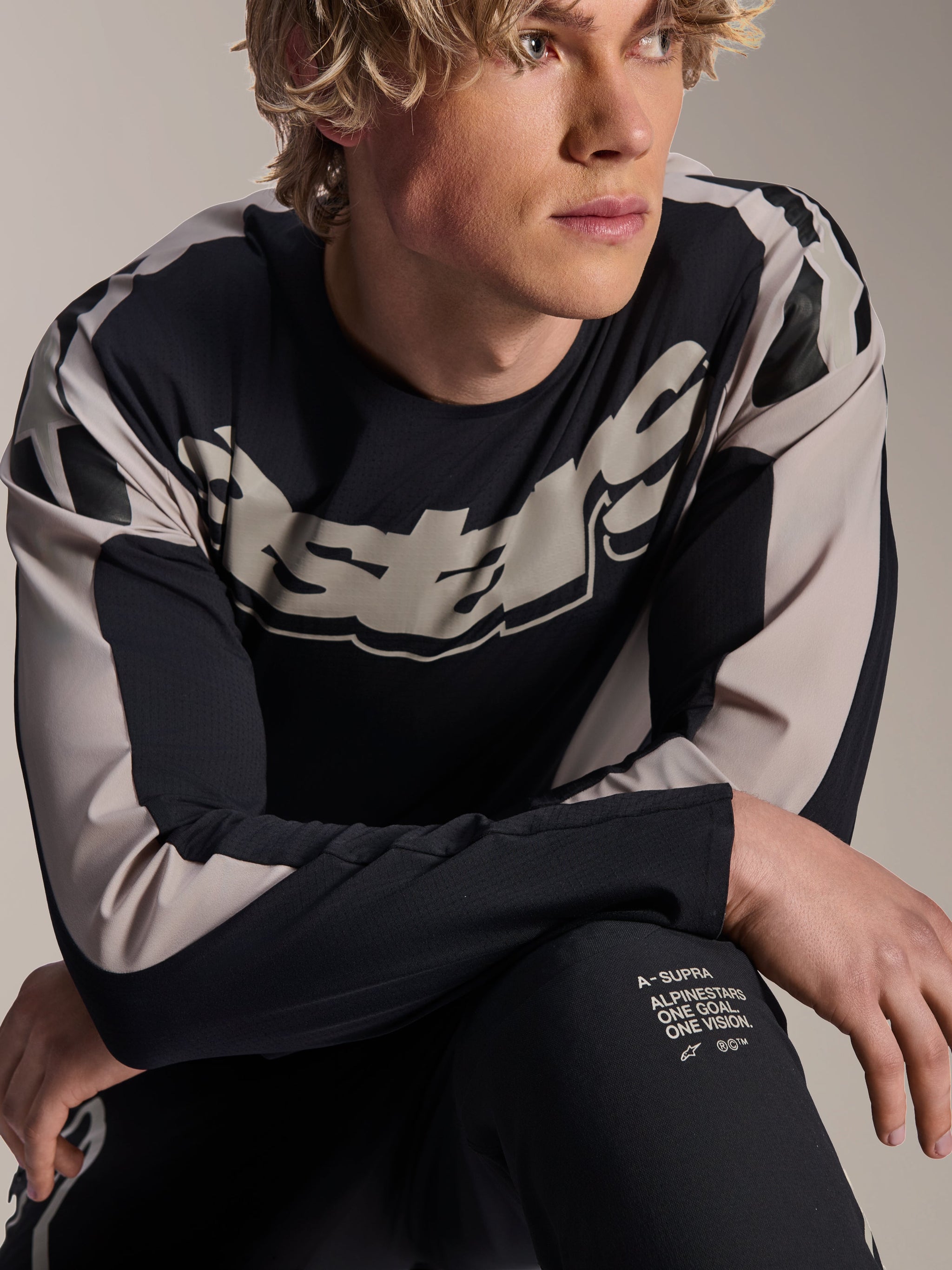 Alpinestars A-Supra Melt Jersey, Long Sleeve MTB Jersey, Black with light grey graphics, worn by model, featuring bold chest logo and 'One Goal. One Vision.' branding, performance mountain bike apparel