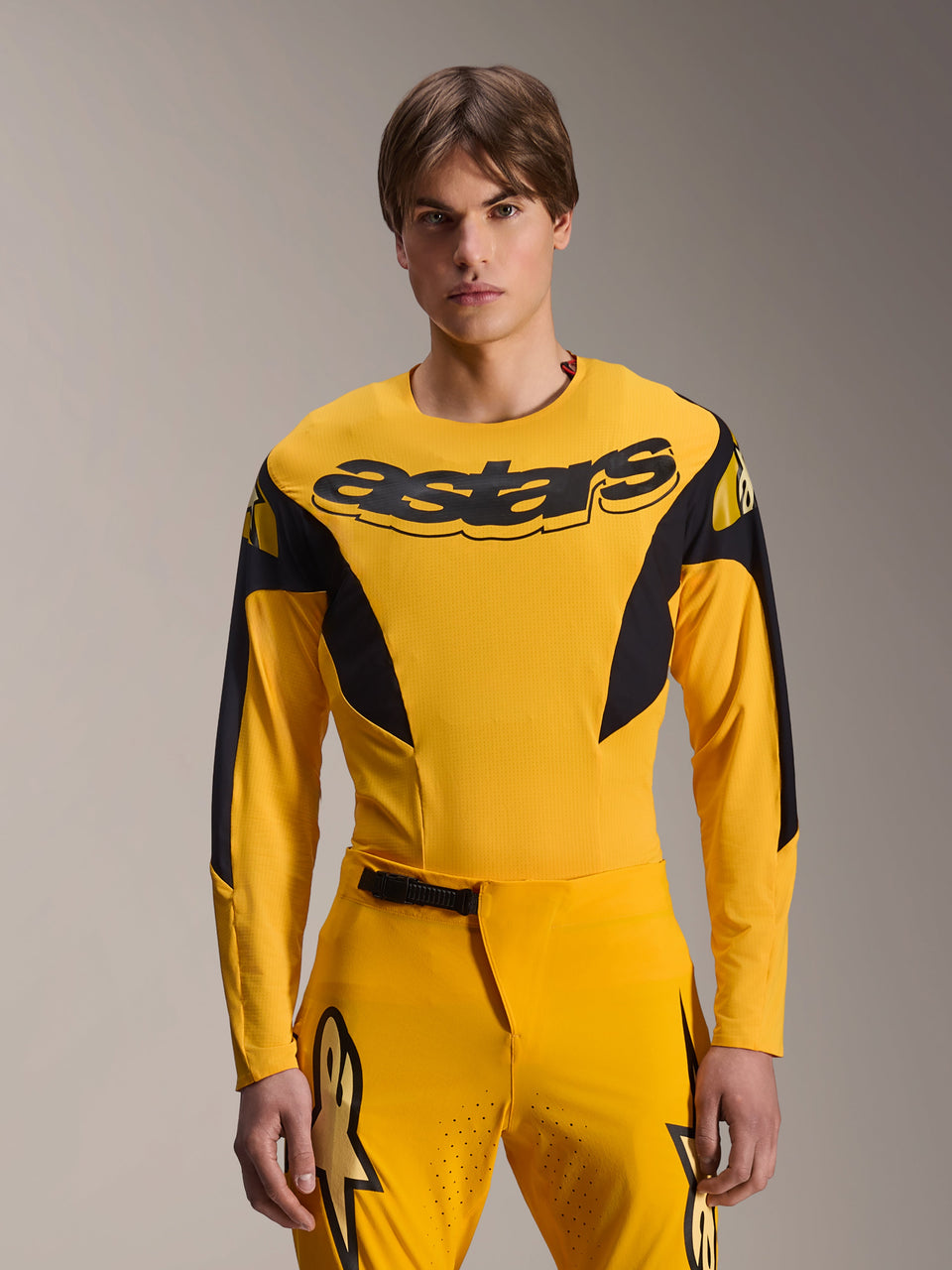 Alpinestars Limited Edition A-Supra Melt Gold Jersey, Long Sleeve MTB Jersey, Dark Yellow with black accents, worn by a model with matching pants, featuring large black 'astars' logo on the chest and athletic performance design