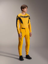 Model wearing Alpinestars Limited Edition A-Supra Melt Gold Jersey, long sleeve MTB jersey in Dark Yellow and Black, paired with matching yellow pants and black shoes, technical off-road cycling gear with racing-inspired graphics