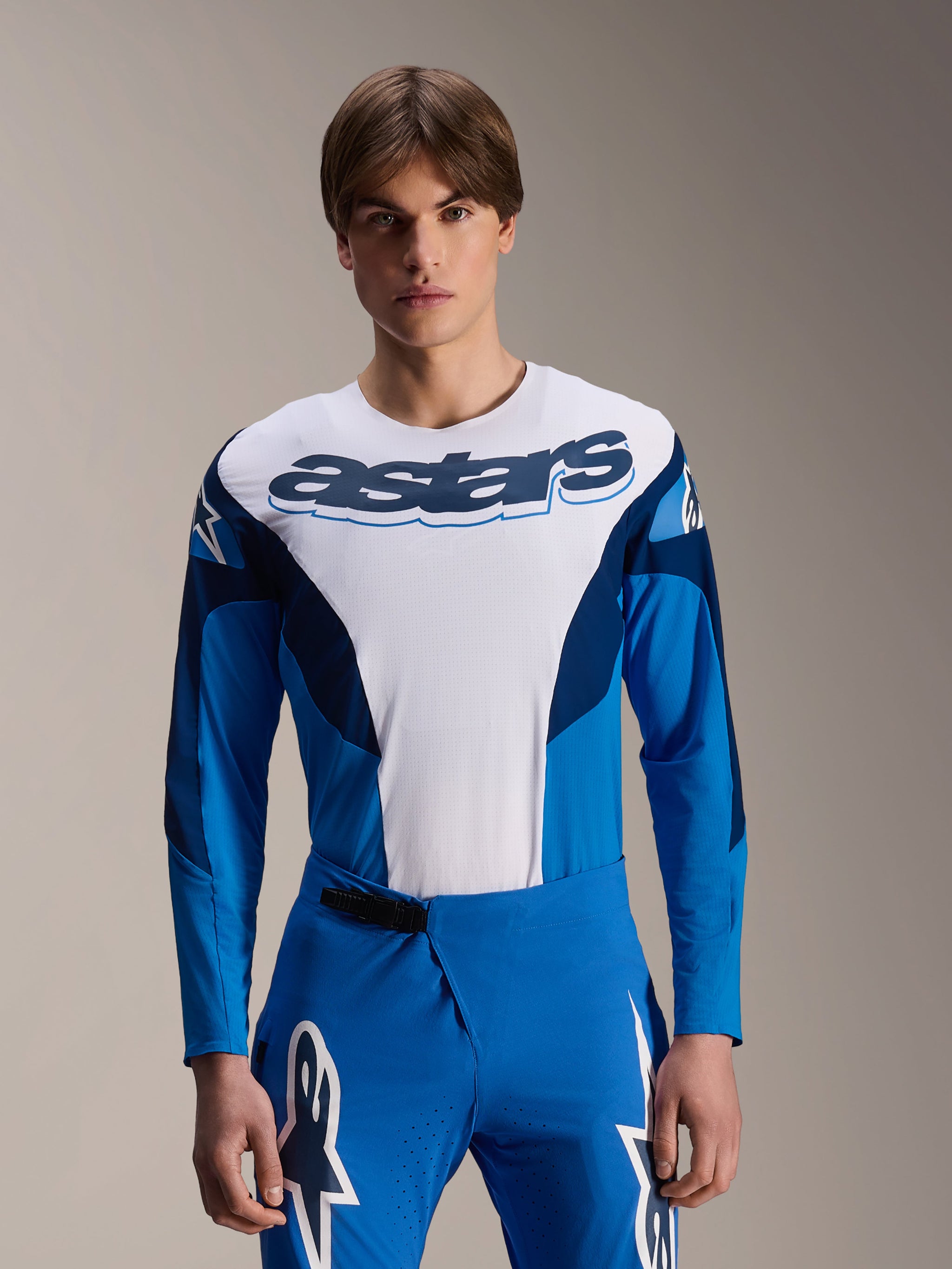 Alpinestars A-Supra Melt Jersey Long Sleeve, Blue and White MTB Jersey, featuring bold astars branding across the chest, dark blue sleeves, worn with matching blue racing pants with white star logos, performance mountain bike apparel
