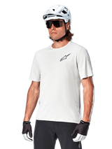 Alpinestars A-Aria Astar Short Sleeve Jersey, White Dove, worn by a cyclist with a white helmet and dark sunglasses, featuring a small black star logo on the chest, breathable performance gear for mountain biking