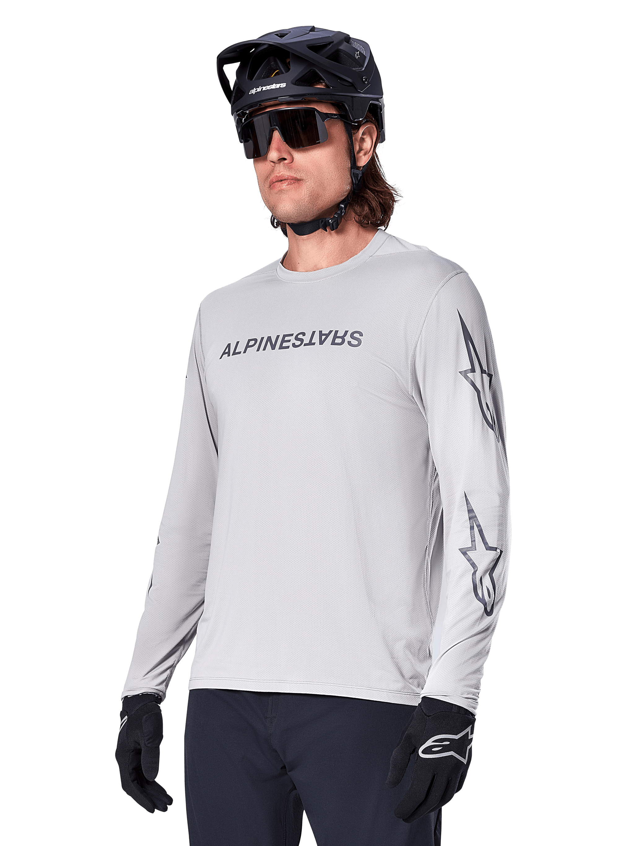 Alpinestars A-Dura Switch Long Sleeve Jersey, Mountain Bike Jersey, Light Gray, black wordmark screen print on chest and star logos on sleeves, worn with black mountain bike helmet, dark sunglasses, and black gloves, athletic off-road cycling gear