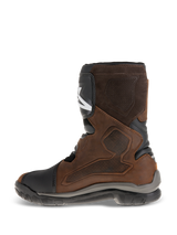 Alpinestars Belize Drystar® Boots, short-calf adventure touring motorcycle boots, oiled brown leather with black and grey accents, showing the medial side with a large heat-press textured grip panel, TPU shin plate, and rugged vulcanized rubber sole