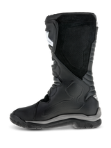 Alpinestars Corozal Adventure Drystar® Boots, Black adventure touring motorcycle boots, medial side profile featuring suede grip panels and accordion flex zones, white shin plate logo, durable grey and black sole