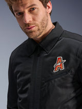Alpinestars Ignite Air Jacket, Black, featuring a traditional shirt collar and breathable mesh construction, highlighted by a red and gold 'A' logo patch on the chest, worn by a male model, urban motorcycle apparel