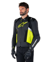 Male model wearing Alpinestars Missile V3 Airflow Leather Jacket, Black with Yellow Fluo and White accents, featuring perforated leather for maximum ventilation, bold yellow logo on the chest, paired with black gloves and pants, sport-style racing motorcycle gear