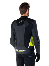 Alpinestars Missile V3 Airflow Leather Jacket, rear view on a male model, black with fluorescent yellow and white accents, featuring extensive perforated leather and mesh panels on the back, branded with a yellow star logo and white 'RACING AHEAD' text, paired with black gloves and pants.