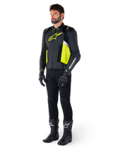 Male model wearing the Alpinestars Missile V3 Airflow Leather Jacket in Black, Yellow Fluo, and White, styled with black riding gloves, pants, and boots, showcasing the perforated leather design and racing-inspired aesthetic.