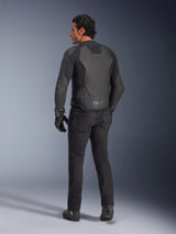Rear view of a model wearing the Alpinestars GP Force V2 Leather Jacket in Black Black, featuring a multi-panel leather construction and sport fit, paired with black riding pants, gloves, and boots for a full motorcycle racing-inspired look.