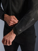 Alpinestars GP Force V2 Leather Jacket, Black, close-up view of the ergonomic sleeve cuff, person adjusting the wrist closure, premium bovine leather construction with technical details for sport motorcycle riding