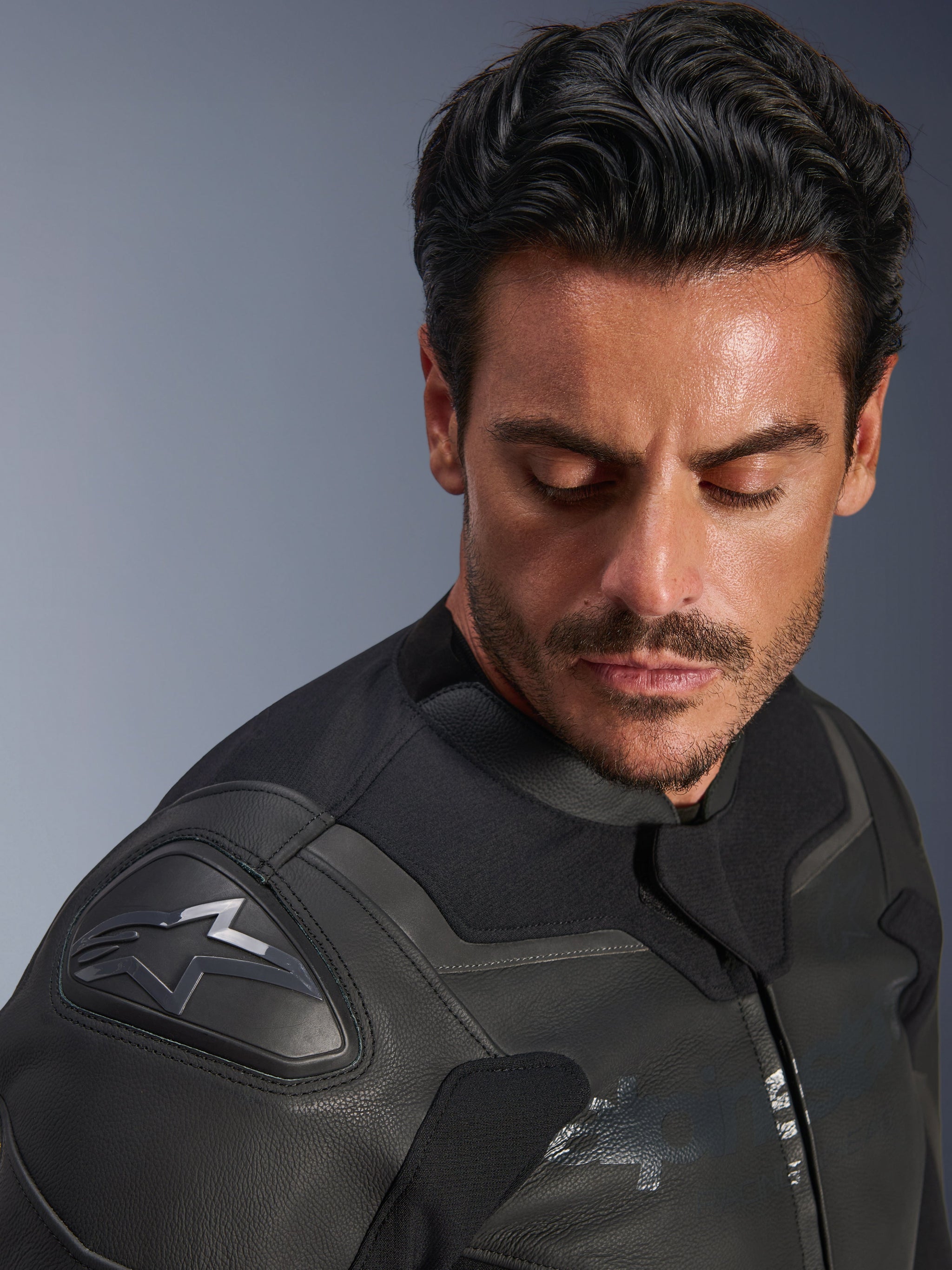 Alpinestars GP Force V2 Leather Jacket, Black, close-up of a male model wearing the jacket, focusing on the shoulder featuring the GP Lite Evo DFS protector and Alpinestars logo, premium multi-panel leather construction