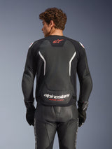 Alpinestars GP Force V2 Air Leather Jacket, Black with White and Red accents, rear view showing perforated leather back panel, white Alpinestars branding, and red logo details, worn with matching black leather racing pants and gloves.