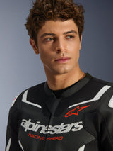 Portrait of a male model wearing the Alpinestars GP Force V2 Air Leather Jacket in Black and White, featuring perforated leather construction, prominent white logo and red 'RACING AHEAD' text on the chest, sport motorcycle riding gear