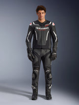 Male model wearing Alpinestars GP Force V2 Air Leather Jacket, Black and White, paired with matching leather pants, gloves, and boots, sporty front view, perforated leather construction with white accents and Alpinestars logos