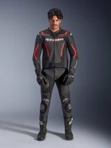 Male model wearing Alpinestars GP Force V2 Air Leather Jacket in Black and Red Fluo, featuring perforated chest panels and white branding, paired with black motorcycle leather pants, black gloves, and black boots for a complete racing look.
